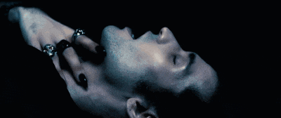 a man with black nails and rings on his fingers laying down