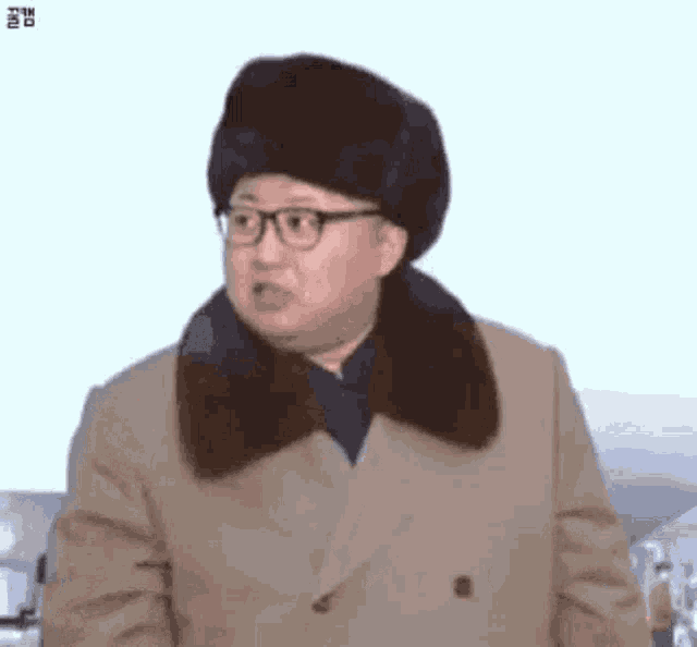 kim jong un is wearing a fur hat and glasses while making a funny face .