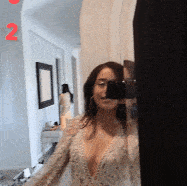 a woman is taking a picture of herself in a mirror with the number 2 behind her