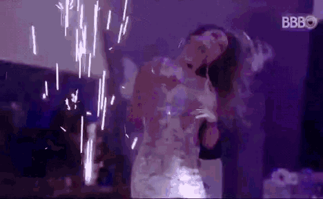 a woman is dancing in front of a fireworks display in a dark room .