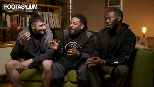 three men are sitting on a green couch and the word foota2ylum is on the bottom