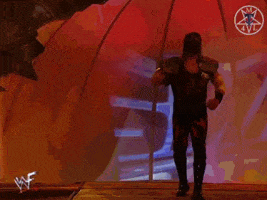 a man in a black and red costume is standing in front of a metal object