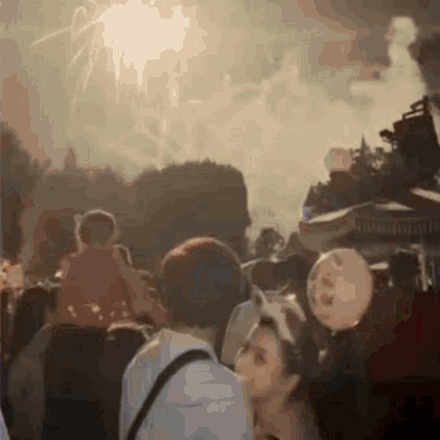 a blurred image of a crowd watching fireworks with a sign that says ' hamburgers ' on it