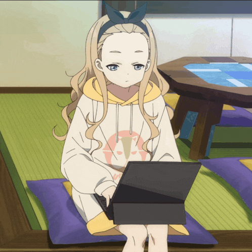 a girl is sitting on a pillow with a laptop