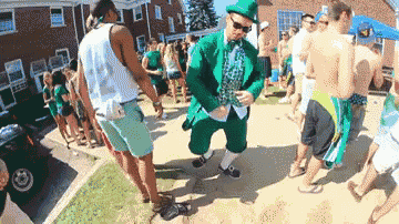 a man in a green leprechaun outfit is dancing in front of a crowd