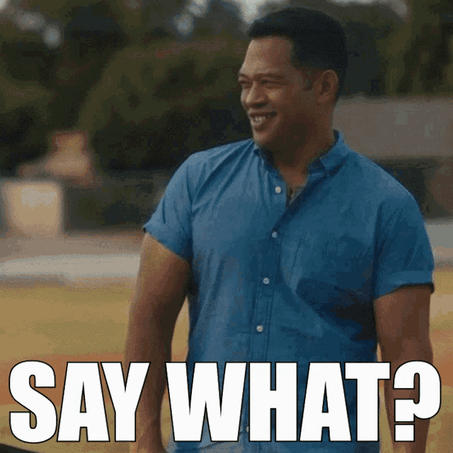 a man in a blue shirt is smiling with the words say what below him