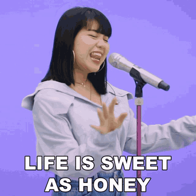 a woman singing into a microphone with the words life is sweet as honey behind her