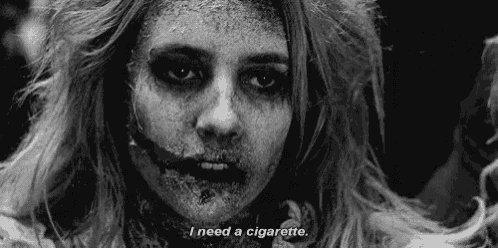 a black and white photo of a zombie woman with cigarette in her mouth .
