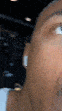a close up of a man 's face with a white ear bud in his ear