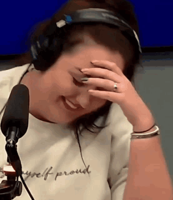 a woman wearing headphones covering her face with her hand