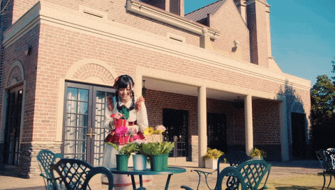 a woman standing in front of a brick building holding a basket of flowers