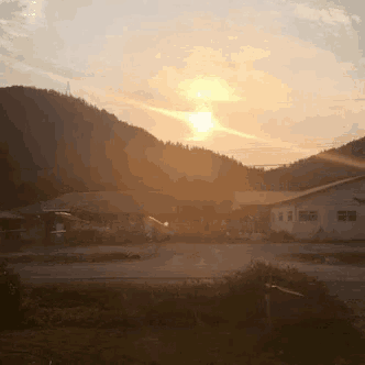 the sun is setting behind a few buildings in the distance