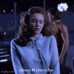 a woman in a blue sweater says " eleena # 1 cherry fan " in a gif