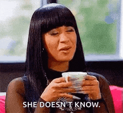 a woman is holding a cup of coffee and saying `` she does n't know '' .