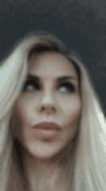 a close up of a woman 's face with long blonde hair and a serious look on her face .