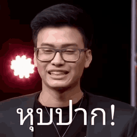 a man wearing glasses and a necklace is making a face .