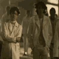 a group of men in white suits are standing next to each other in a dark room .