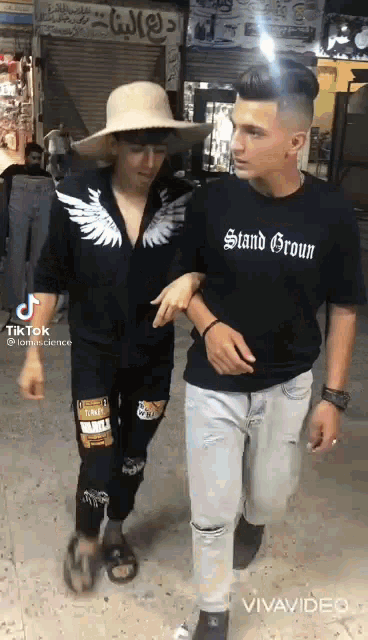 two young men are walking down a street . one of the men is wearing a t-shirt that says stand groun .
