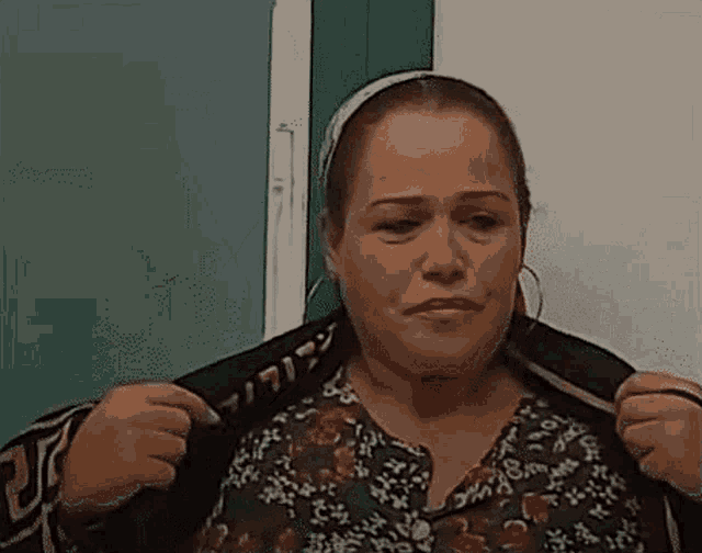 a woman in a floral shirt is holding a black jacket over her shoulder