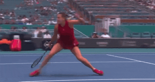 a woman doing a split on a tennis court in front of a pnc bank sign