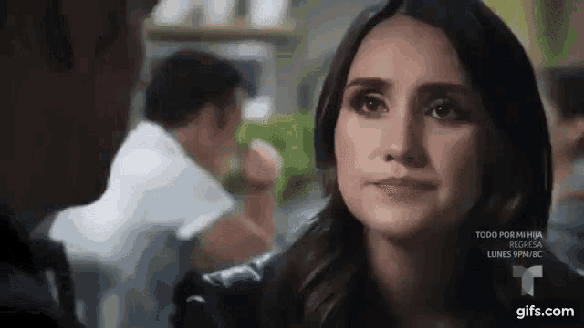 a woman is looking at a man in a restaurant while a man looks on .