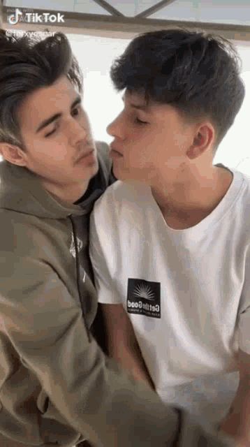 two young men are kissing each other on the cheek while standing next to each other .