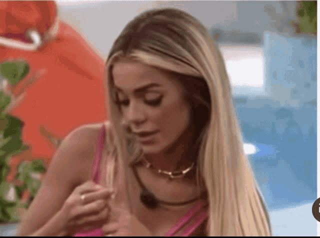 a blonde woman in a pink tank top is looking at something