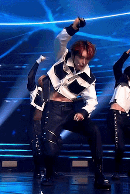 a man with red hair is holding a microphone and dancing on a stage