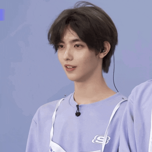 a young man wearing a purple shirt with a skechers logo on it