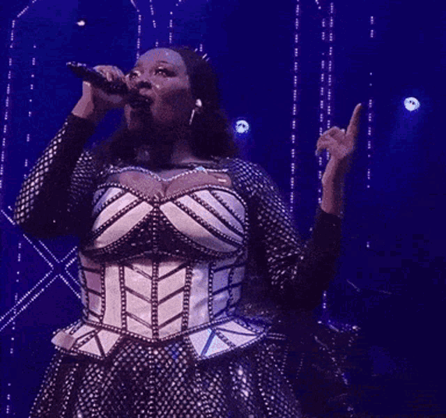 a woman is singing into a microphone on stage .