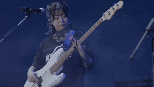 a woman is playing a bass guitar in front of a blue background
