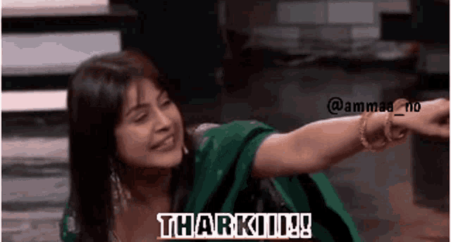 a woman in a green dress is smiling and pointing at the camera with the words thank you written below her .