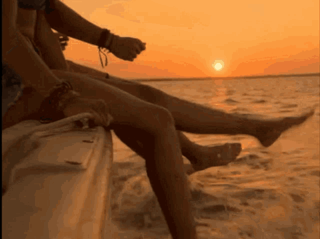 a couple sits on a boat watching the sun set over the ocean