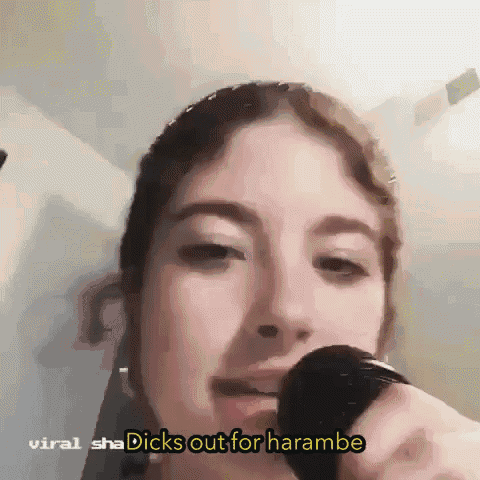a woman singing into a microphone with the words " dicks out for harambe " on the bottom right