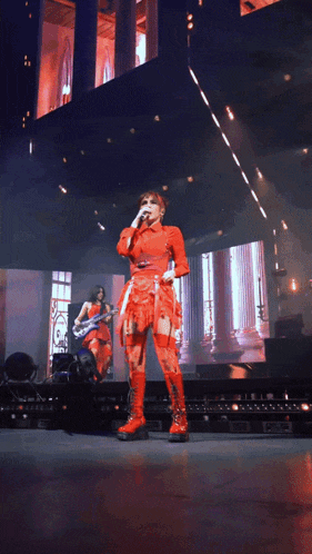 a woman in a red dress is singing into a microphone on stage