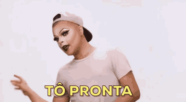 a drag queen wearing a baseball cap and a white shirt is making a funny face and says `` to pronta ''