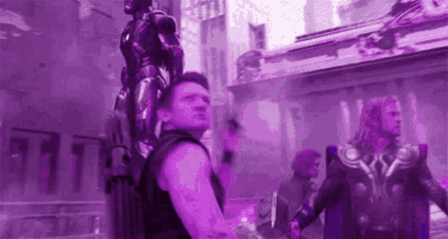 a man in a black tank top is standing in front of a purple building .