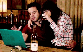 a man and a woman are sitting at a table with a bottle of wine and a laptop