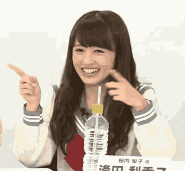 a girl in a school uniform is holding a bottle of water with a straw in it