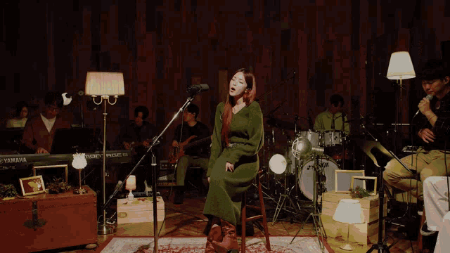 a woman in a green dress sings into a microphone in front of a yamaha keyboard