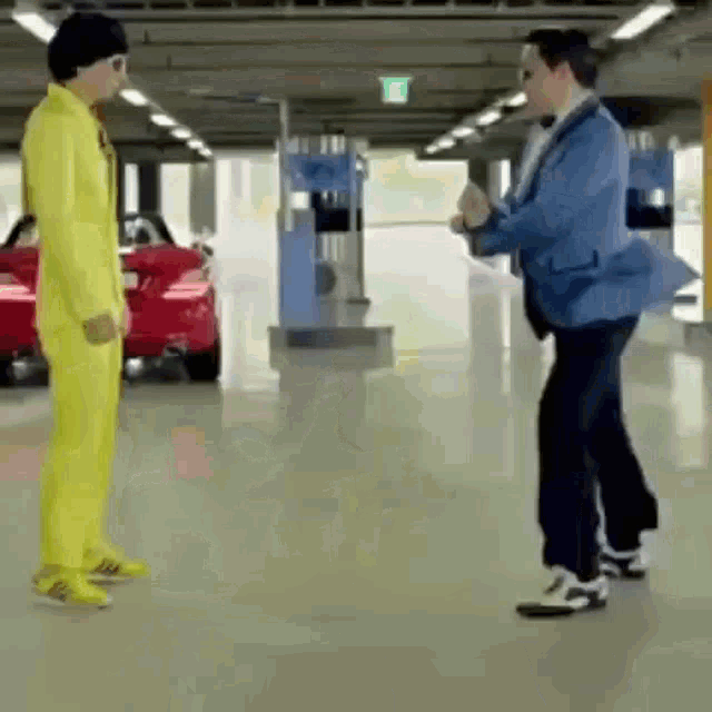 a man in a yellow suit is dancing with another man in a blue suit in a parking garage .