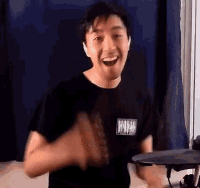 a man in a black shirt is playing a drum set .