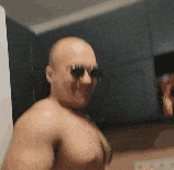 a shirtless bald man wearing sunglasses is taking a picture of himself