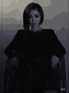 a woman is sitting in a chair with her hands on her knees .