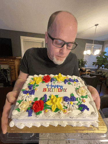 a man holding a birthday cake that says happy birthday on it