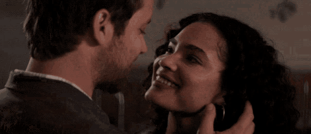 a man with a beard is smiling while looking at a woman