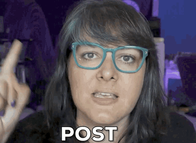 a woman with blue hair and glasses says post with her finger