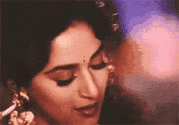 a close up of a woman 's face with her eyes closed and a purple background .