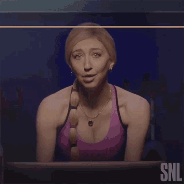 a woman in a purple tank top with the letters snl on the bottom
