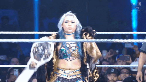 a woman with blue hair is standing in a wrestling ring